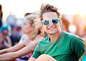 Teenage boy at summer music festival, sitting on ground