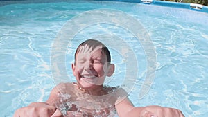Teenage boy swims in the pool smiling and happy