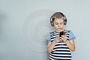 Teenage boy texting using smartphone listening to music wearing headphones