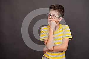 A teenage boy thought about it. Serious face. Isolated over dark grey background, copy space.