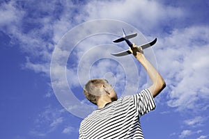 Teenage boy throwing airplane to the sky on sunny summer day. Childhood dreams, summer holiday entertainment outdoors