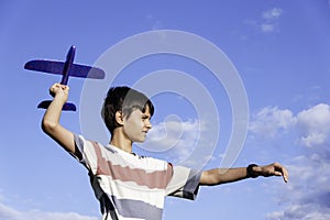 Teenage boy throwing blue airplane to the sky on summer sunny day. Childhood dreams, summer holiday entertainment