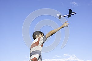 Teenage boy throwing blue airplane to the sky on summer sunny day. Childhood dreams, summer holiday entertainment