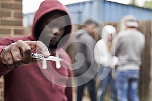 Teenage Boy In Urban Gang Pointing Knife Towards Camera