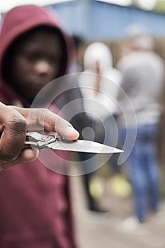 Teenage Boy In Urban Gang Pointing Knife Towards Camera