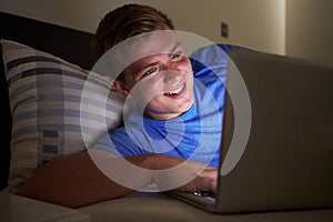 Teenage Boy Using Laptop In Bed At Night