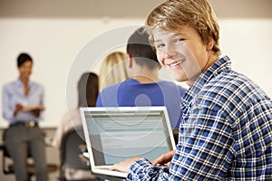 Teenage boy using laptop in class