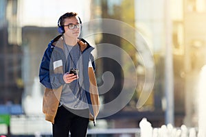 Teenage boy using smartphone and listening to music outdoors. Copy space