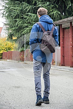 Teenage boy walking alone in street with backpack