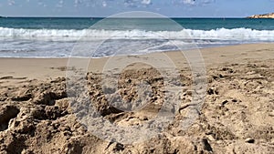 A teenage boy walks along a sandy beach by sea, close-up of feet, Cyprus