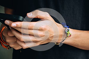 Teenage boy with wristlet with autism infinity rainbow symbol sign on his hand. World autism awareness day, autism