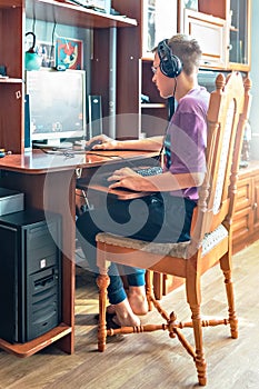 A teenage boy, a young man playing video games on a computer, using technology, wearing headphones, using a computer.A young man,