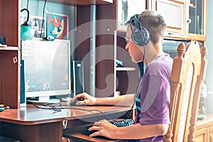 A teenage boy, a young man playing video games on a computer, using technology, wearing headphones, using a computer.A young man,