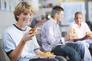 Teenage boys enjoying fast food lunches together