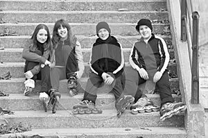 Teenage boys and girls in roller skates sitting on stairs