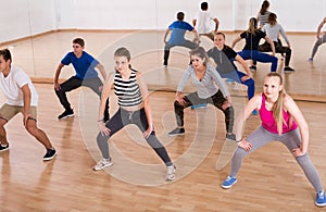 Teenage boys and girls with trainer stretching in dance hall