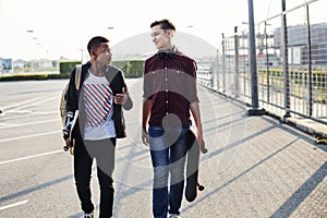 Teenage boys holding skateboard walking