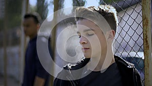 Teenage boys leaning on metal fence, juvenile detention center, orphanage