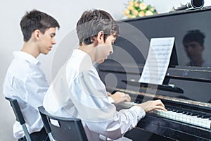 Teenage boys play piano in class or at home .