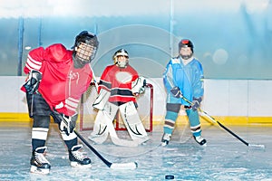 Teenage boys playing hockey on ice rink of stadium