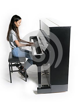 Teenage brunette girl and black upright piano in studio