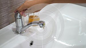 A teenage child opens the tap and washes his hands with soap under running water in sink. Clean your hands to prevent