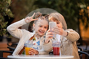 Teenage children chat happily together sitting at a table in a summer cafe