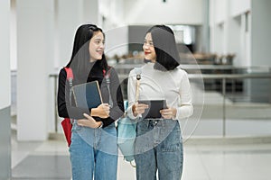 Teenage college friend students walking and chatting in college campus while having break after class. Two happy students walking