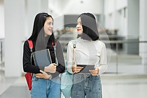 Teenage college friend students walking and chatting in college campus while having break after class. Two happy students walking