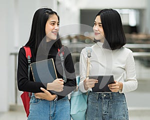 Teenage college friend students walking and chatting in college campus while having break after class. Two happy students walking