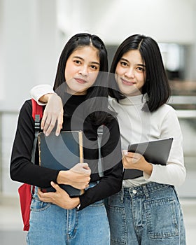 Teenage college friend students walking and chatting in college campus while having break after class. Two happy students walking