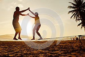 Teenage couple balancing slackline on the beach