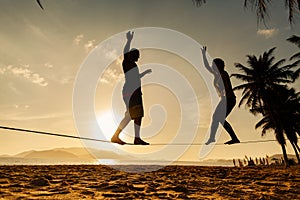 Teenage couple balancing slackline on the beach photo