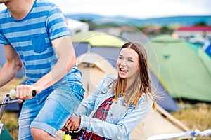 Teenage couple riding bike together at summer music festival