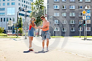 Teenage couple riding skateboards on city street