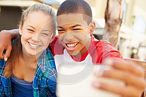 Teenage Couple Sitting On Bench In Mall Taking Selfie