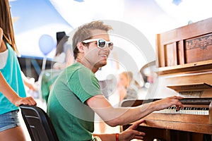 Teenage couple at summer music festival, boy plays piano