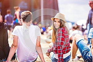 Teenage couple at summer music festival, sitting in front of sta