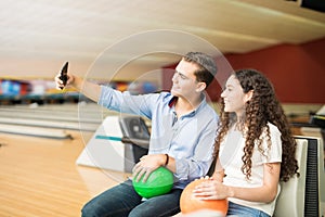 Teenage Couple Taking Selfportrait Using Smartphone In Bowling C