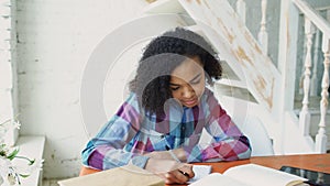 Teenage curly haired mixed race young girl sitting at the table concentrating focused learning lessons for examination