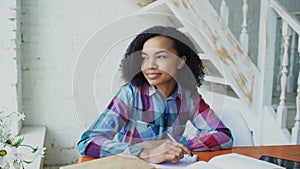 Teenage curly haired mixed race young girl sitting at the table concentrating focused learning lessons for examination