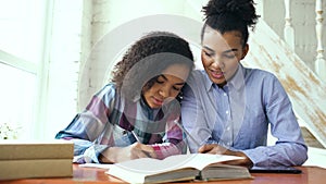 Teenage curly haired mixed race young girl sitting at the table concentrating focused learning lessons and her elder