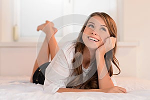 Teenage dreams. Cheerful teenage girl lying on the sofa with her