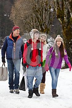 Teenage Family Carrying Shopping Along Street