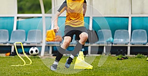 Teenage football player running on the training pitch. Young boy practicing soccer using sports equipment