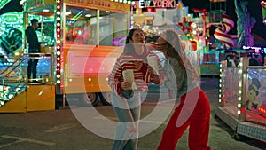 Teenage friends hang out together at amusement luna park. Joyful girls laughing