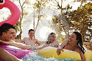 Teenage friends have fun with inflatables in a swimming pool