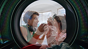 Teenage friends listening music in laundry room closeup. Smiling couple washing