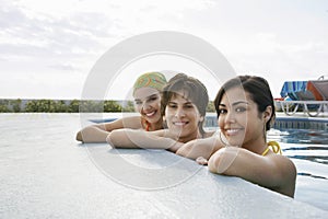 Teenage Friends Resting At The Edge Of Swimming Pool