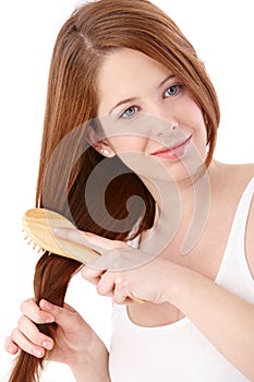 Teenage ginger girl combing long hair